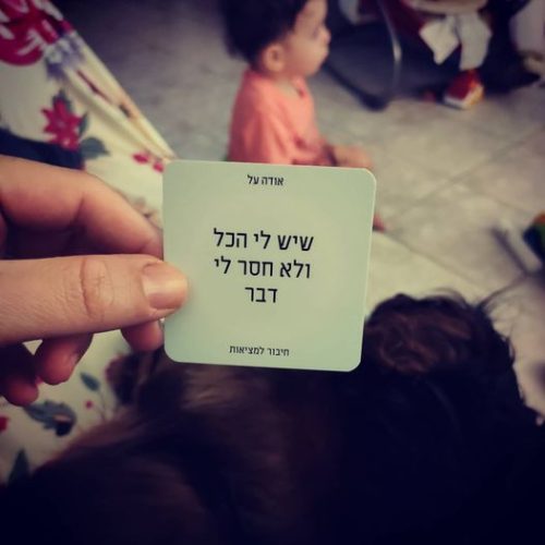 יד אישה מחזיקה קלף הודיה, תינוק בסיר ברקע וכלב יושב על הברכיים